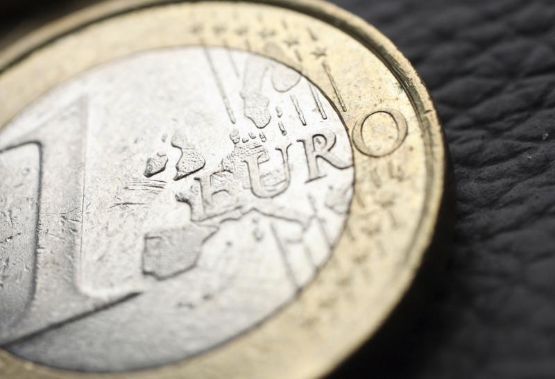 Comicfigur mit Krawatte und Aktentasche zeigt auf ein großes rotes Eurozeichen