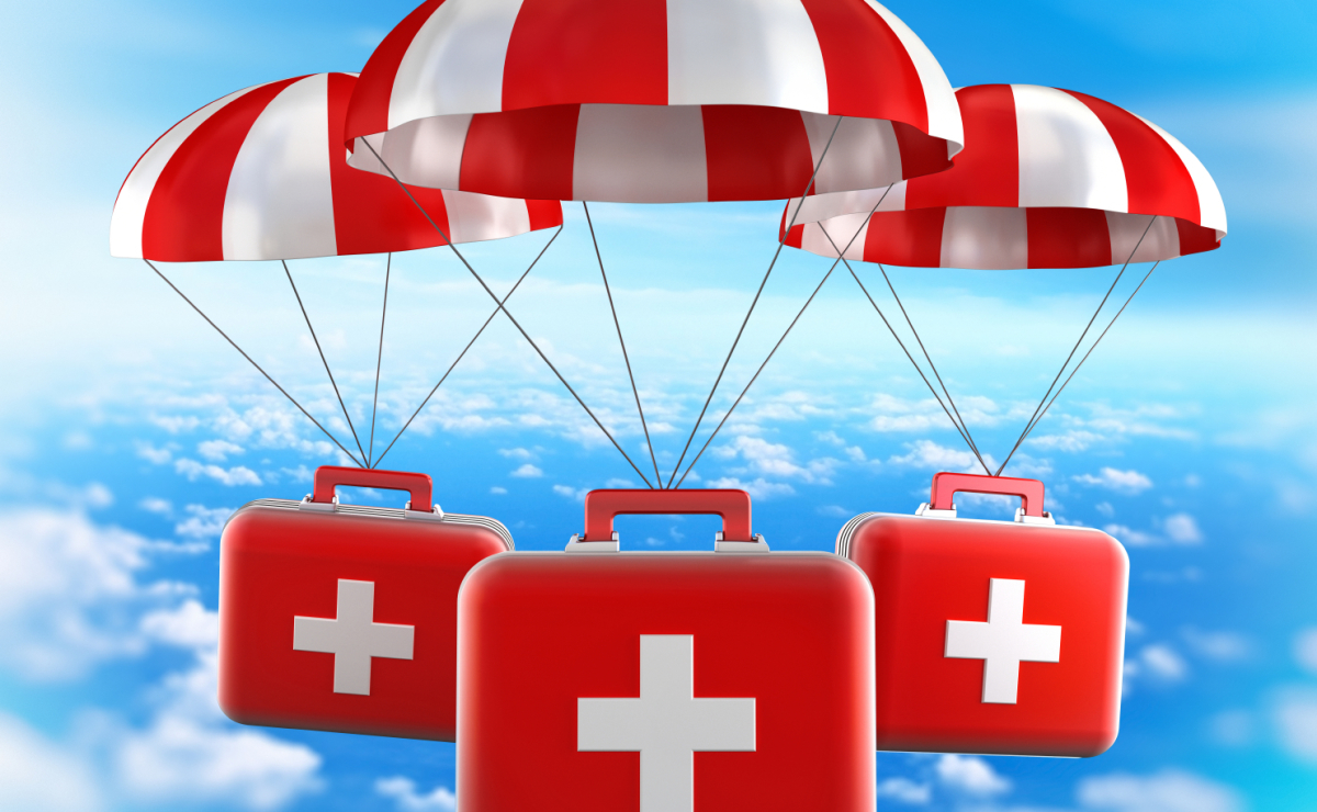 Rote Erste-Hilfe-Koffer mit weißen Kreuzen schweben an Fallschirmen durch den Himmel.